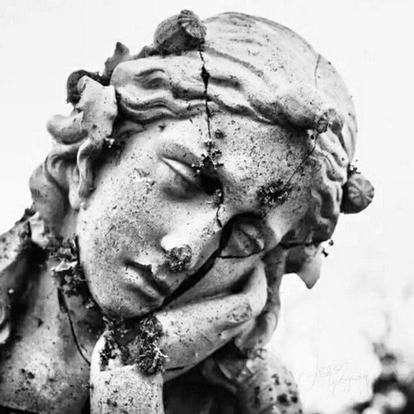 a black and white photo of a statue with dirt on it's face,