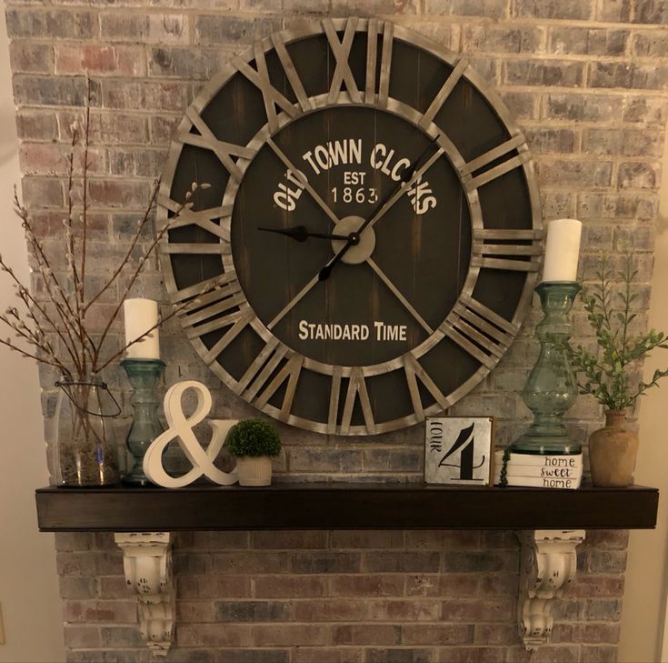 a large clock mounted to the side of a brick wall next to a fire place