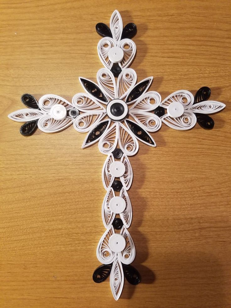 a cross made out of paper on top of a wooden table with black and white decorations