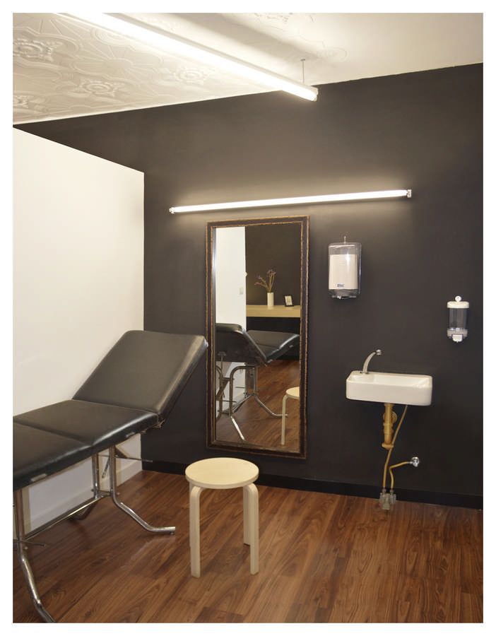 an empty room with a mirror, stool and table in the corner next to it