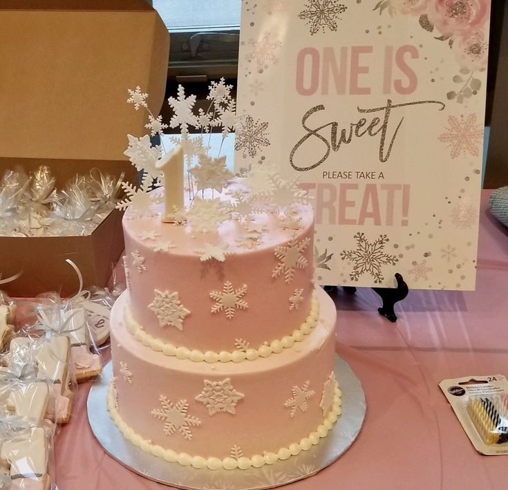 a pink and white cake sitting on top of a table next to a sign that says one is sweet