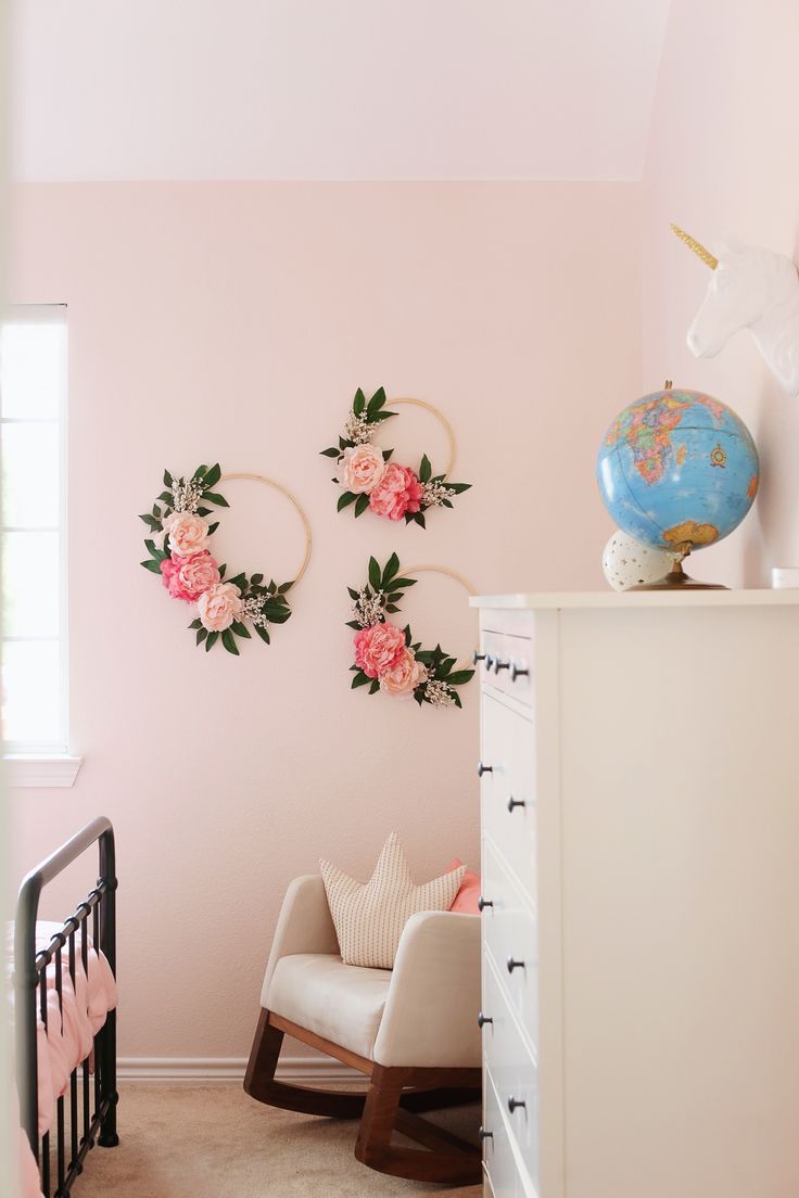 a baby's room with pink walls and floral wall hangings on the wall