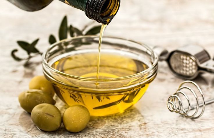 a glass bowl filled with olives and oil