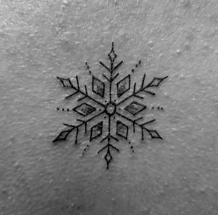 a snowflake tattoo is shown on the back of a woman's stomach