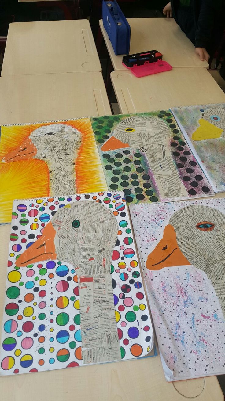 children's art work displayed on wooden desks in class room with colored paper