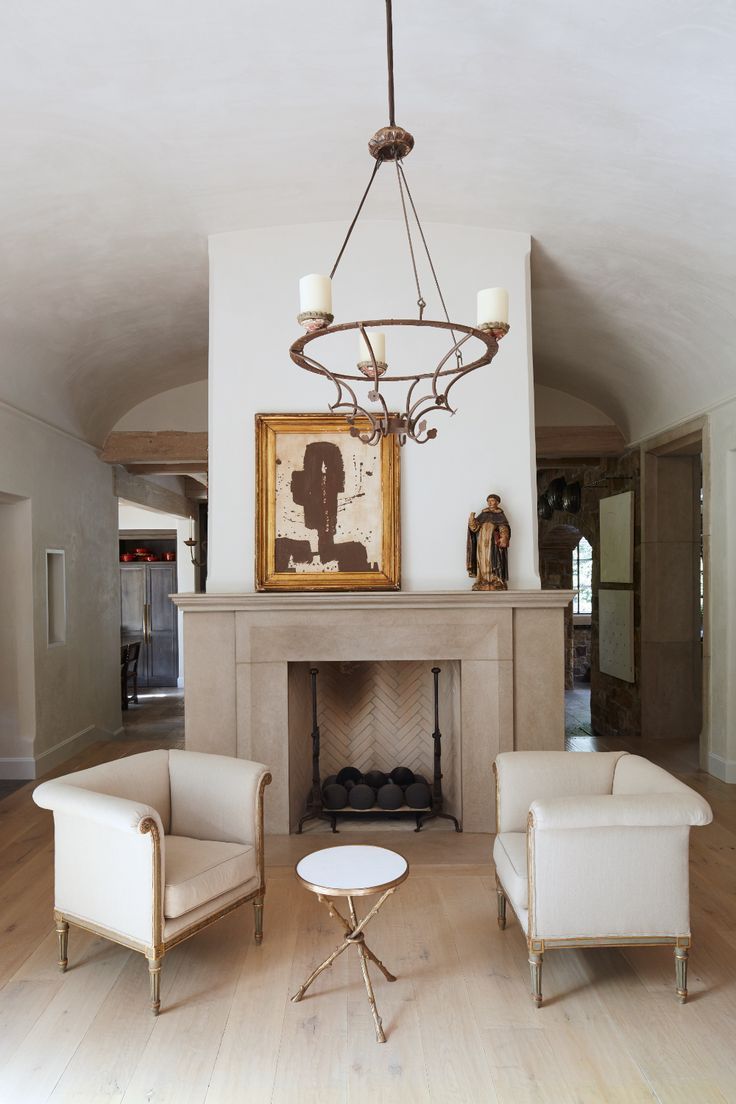 a living room with two white chairs and a fire place in the middle of it