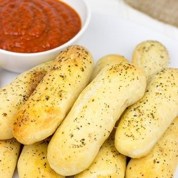 some breadsticks are on a plate next to a bowl of sauce