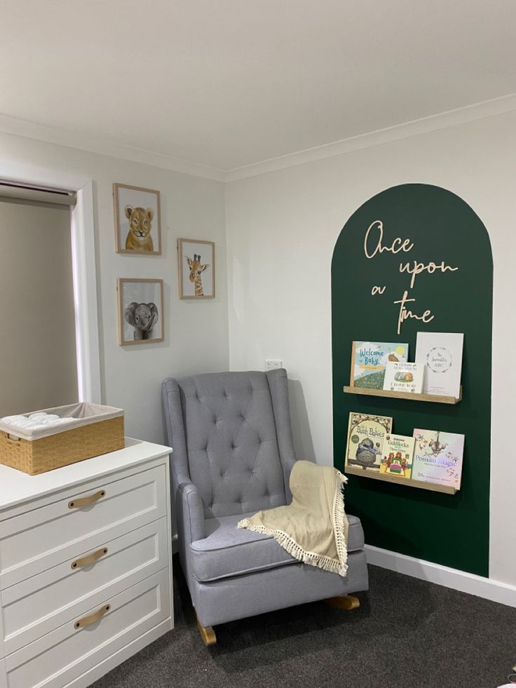 a baby's room with a gray chair and green chalkboard on the wall