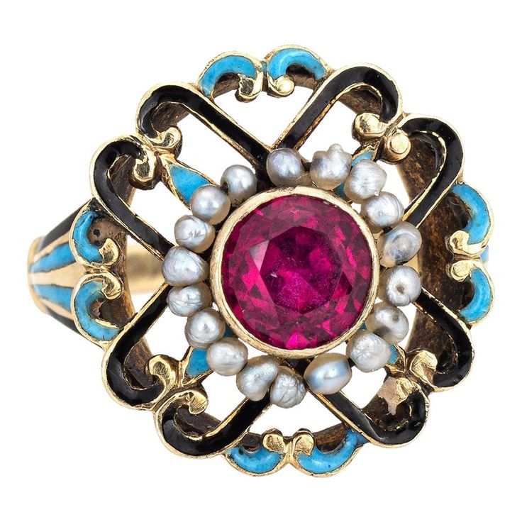 This is part of Chairish’s Fine Jewelry assortment.  Elegant and finely detailed Edwardian era enamel ring (circa 1900s to 1910s), crafted in 14 karat yellow gold.    Created ruby measures 5mm (in very good condition and free of cracks or crisps). Small natural 1mm seed pearls surround the ruby.   A created ruby is set into a beautifully detailed scrolled mount. Blue and black enamel adds a pop of colour, offering contrast to the ruby that is striking and unique. The ring is small in size (2 1/2 Vintage Gemstone Enamel Ring As A Gift, Vintage Enamel Gemstone Ring For Gift, Ornate Yellow Gold Ruby Ring Gift, Antique Enamel Ring Collectible, Victorian Oval Yellow Gold Enamel Ring, Antique Yellow Gold Enamel Wedding Ring, Victorian Yellow Gold Ruby Ring With Intricate Design, Vintage Yellow Gold Enamel Rings, Victorian Ruby Ring In Yellow Gold With Intricate Design