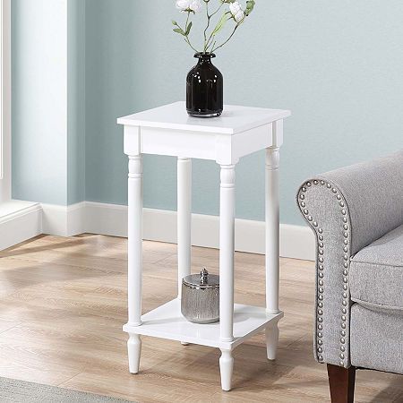 a white end table with flowers in a black vase