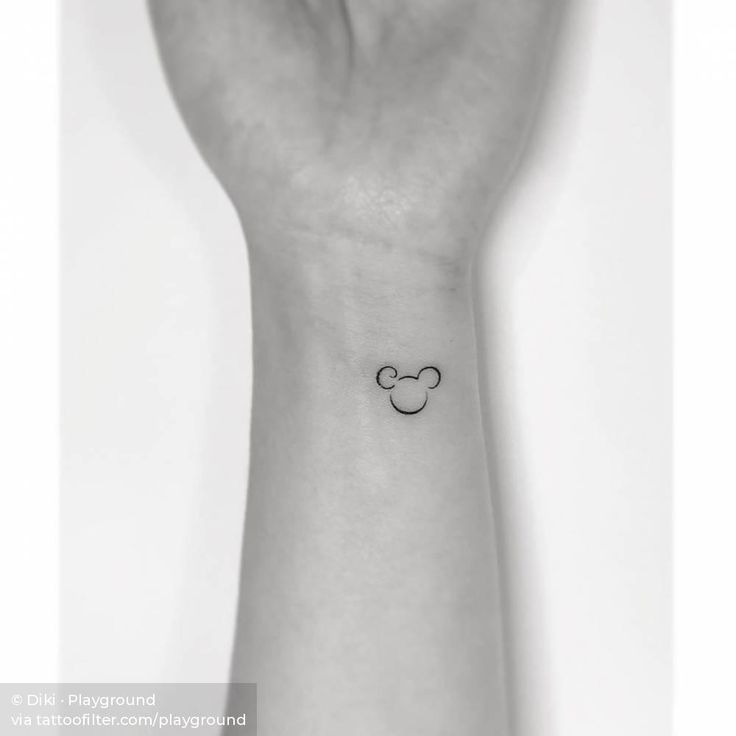 a small wrist tattoo with a mickey mouse head on the left side of the wrist