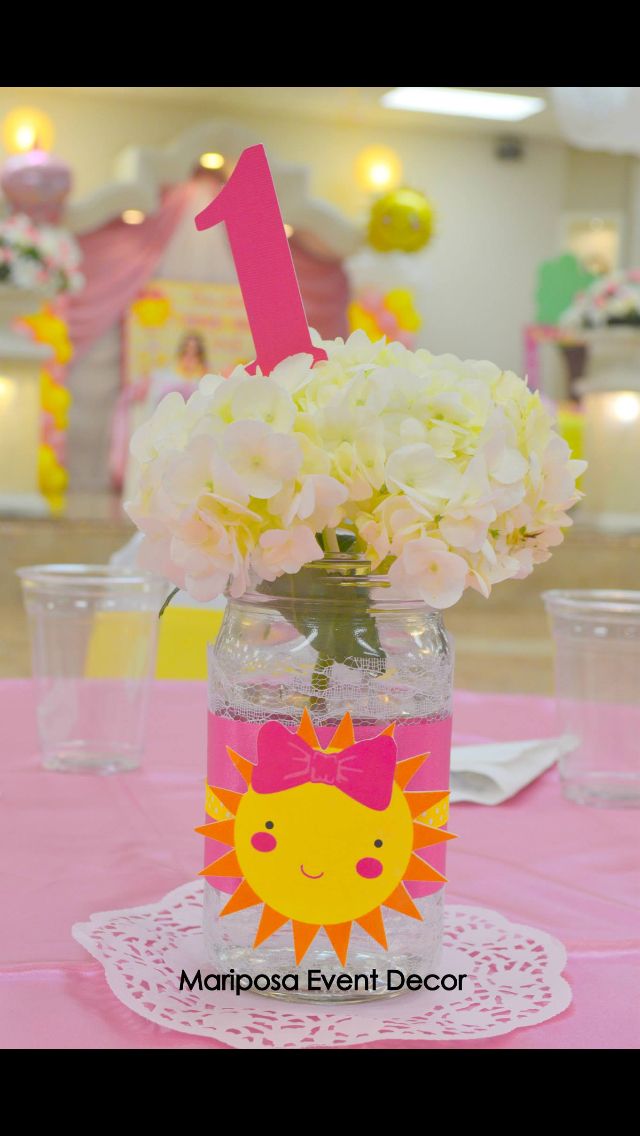 a vase with flowers in it sitting on top of a pink table cloth covered table