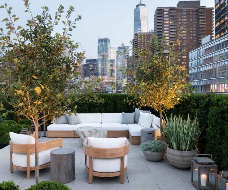 an outdoor living area with couches, tables and potted trees in the foreground