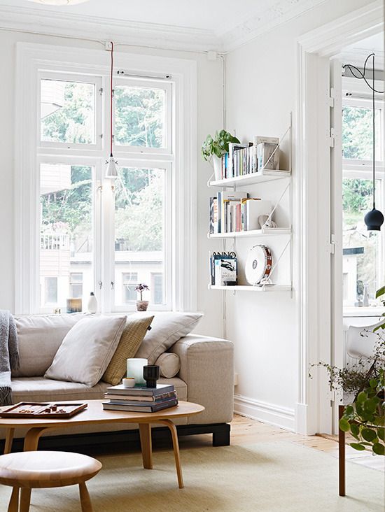 a living room filled with lots of furniture next to two large windows covered in books