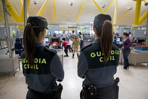 two police officers are standing in an airport waiting for their turn to the next destination