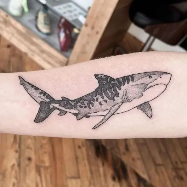 a black and white shark tattoo on the arm