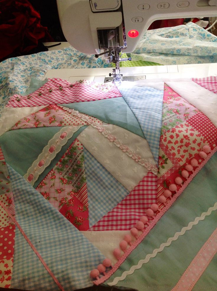 a close up of a sewing machine on a table with quilts and fabrics in the background