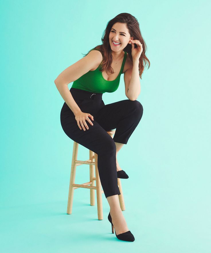 a woman sitting on top of a wooden stool next to a chair and talking on a cell phone