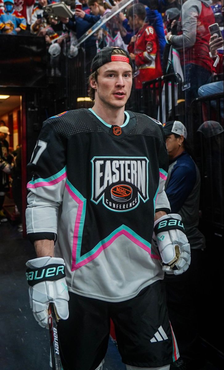 a hockey player is standing in front of an ice rink with his hands on his hips