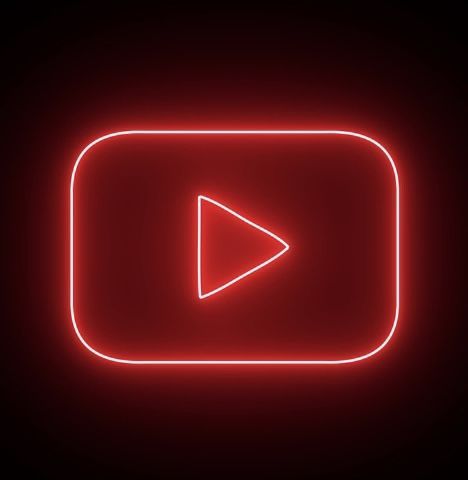 a red neon sign with an arrow in the center on a black background that says youtube