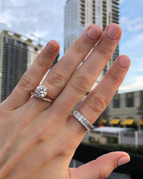 a woman's hand with two rings on top of her fingers, and the other ring