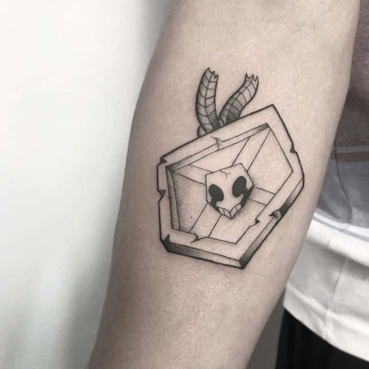 a black and white image of a skull in a box tattoo on the arm