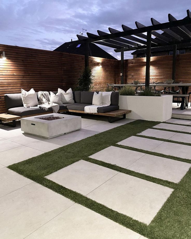 an outdoor living area with grass and white tiles on the floor, covered in wooden slats