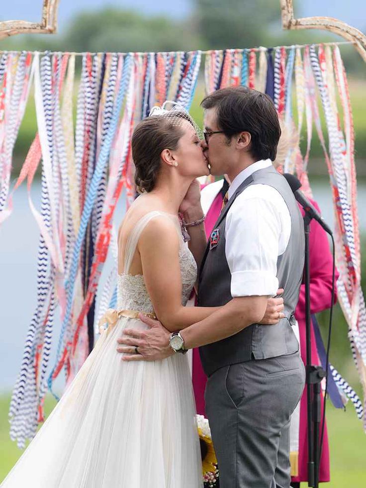 a bride and groom kissing in front of an arch decorated with streamers