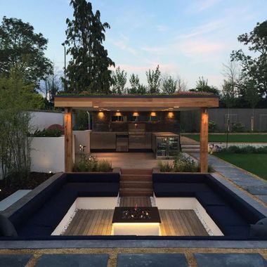 an outdoor living area with a fire pit and grill in the back yard at dusk