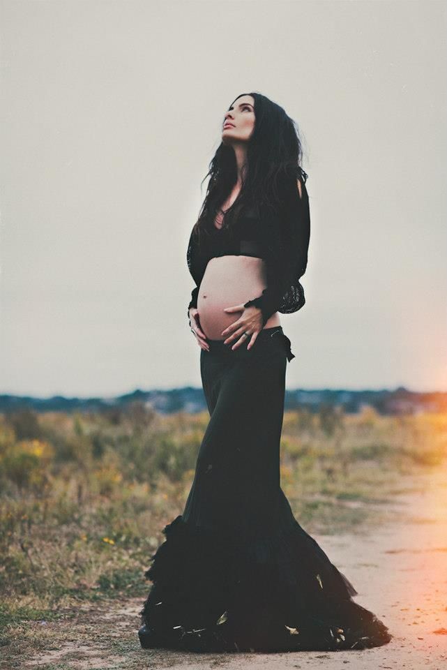 a pregnant woman standing in the middle of a dirt road with her belly wrapped up