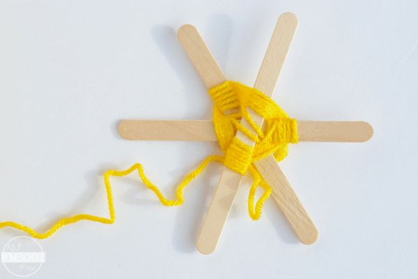 three wooden sticks with yarn on them and one yellow skewer next to it