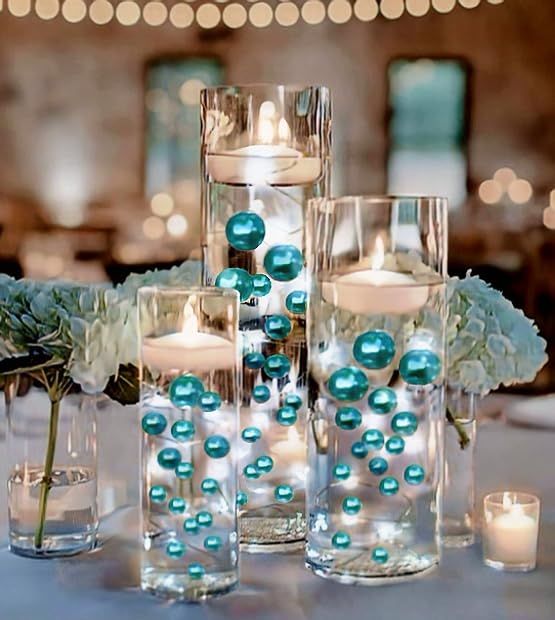 the centerpieces are filled with candles, flowers and balls in glass vases