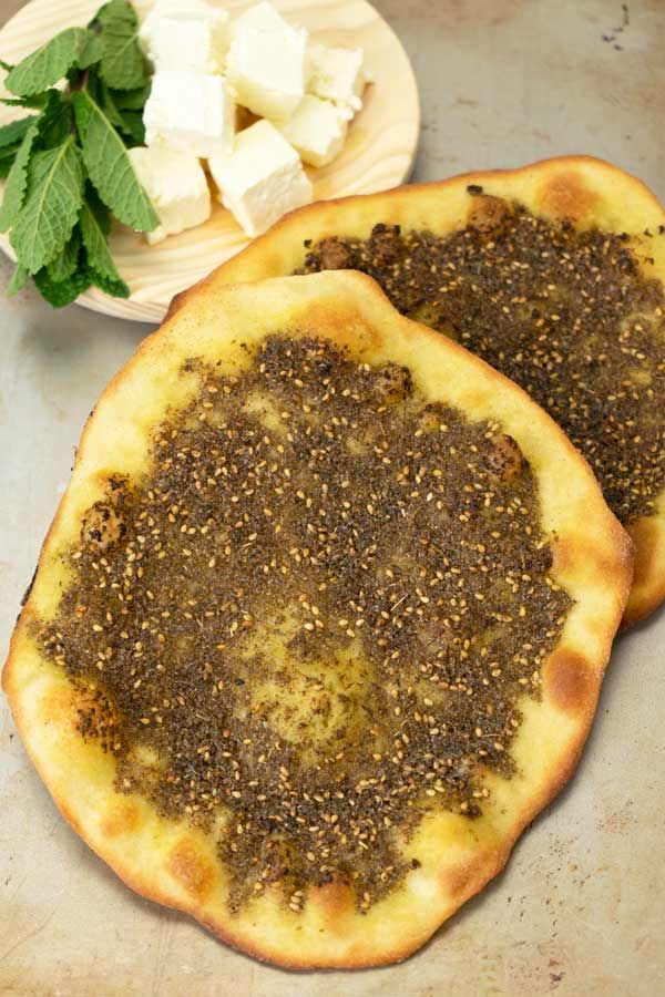 two flatbread pizzas sitting on top of a table