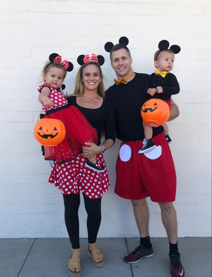 a man and woman with two children dressed up as mickey mouse