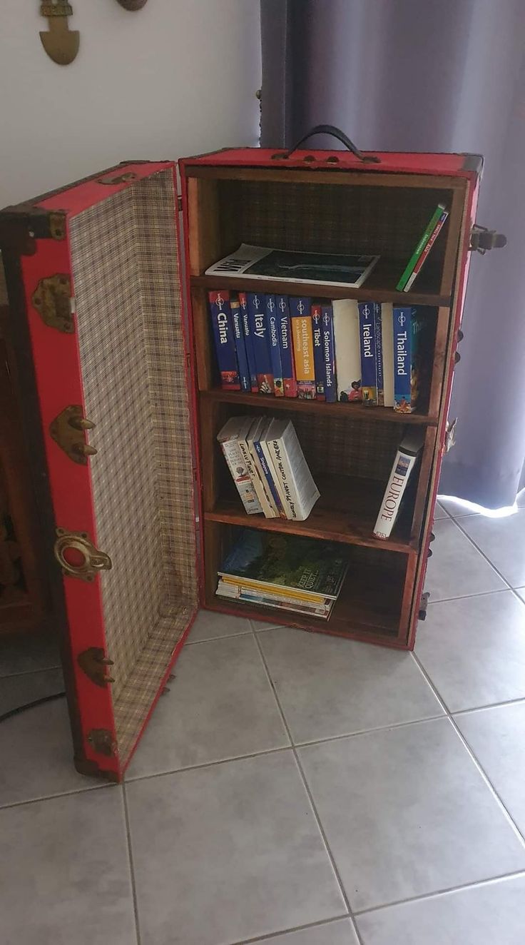 an open suitcase sitting on top of a floor next to a shelf filled with books