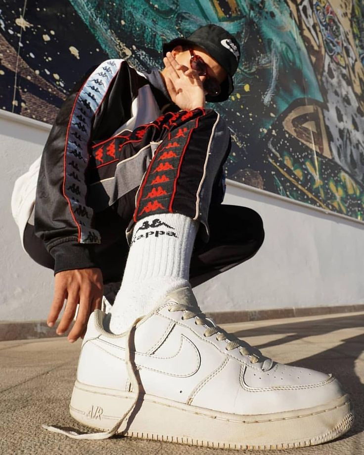 a man sitting on the ground wearing white sneakers