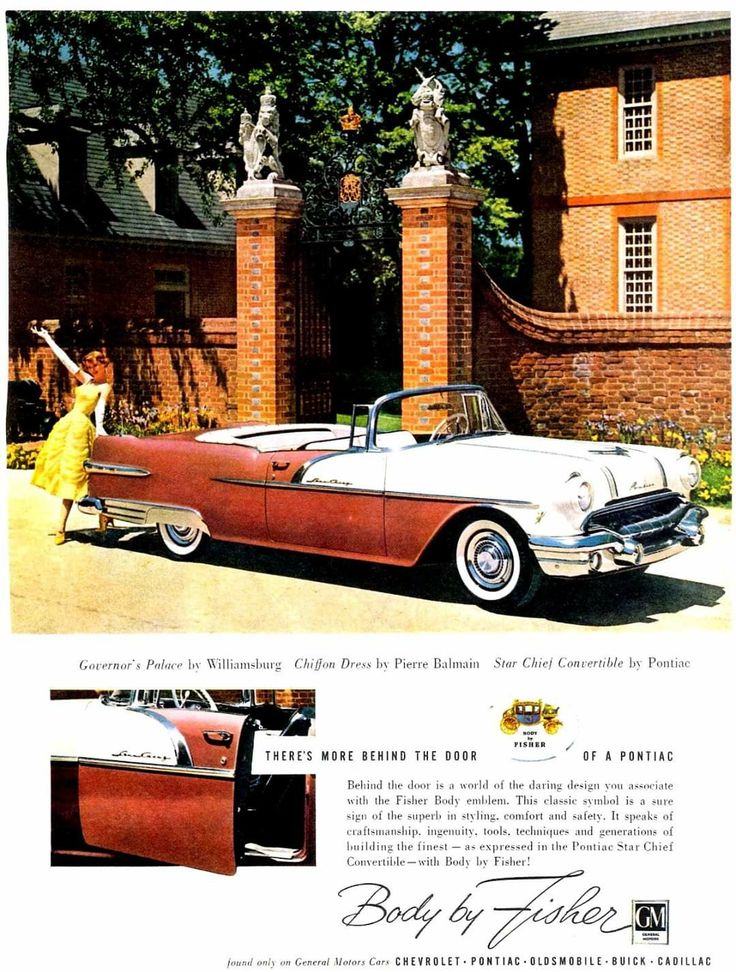 an old car parked in front of a brick building with two women standing next to it