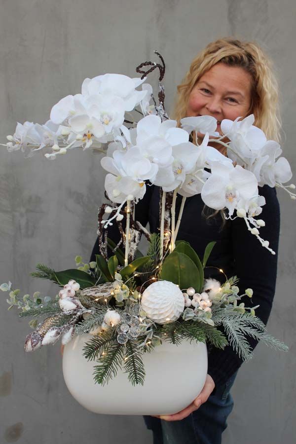 a woman holding a white vase filled with flowers