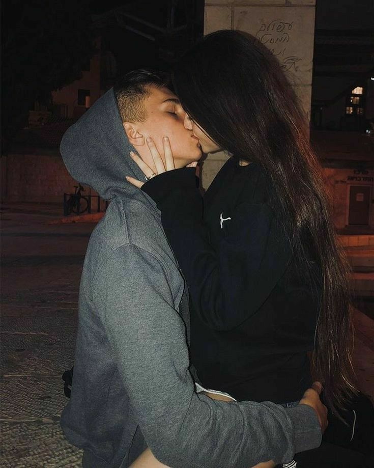 a man and woman kissing each other on the street