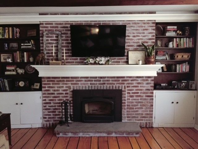 a living room with a fire place and bookshelves on the wall above it