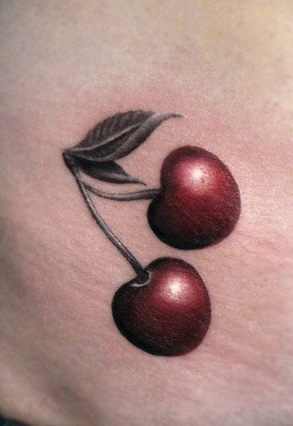 two cherries on the side of a woman's stomach, one with a leaf