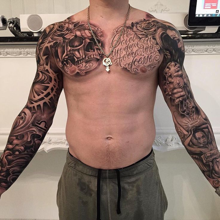 a man with tattoos on his chest standing in front of a mirror