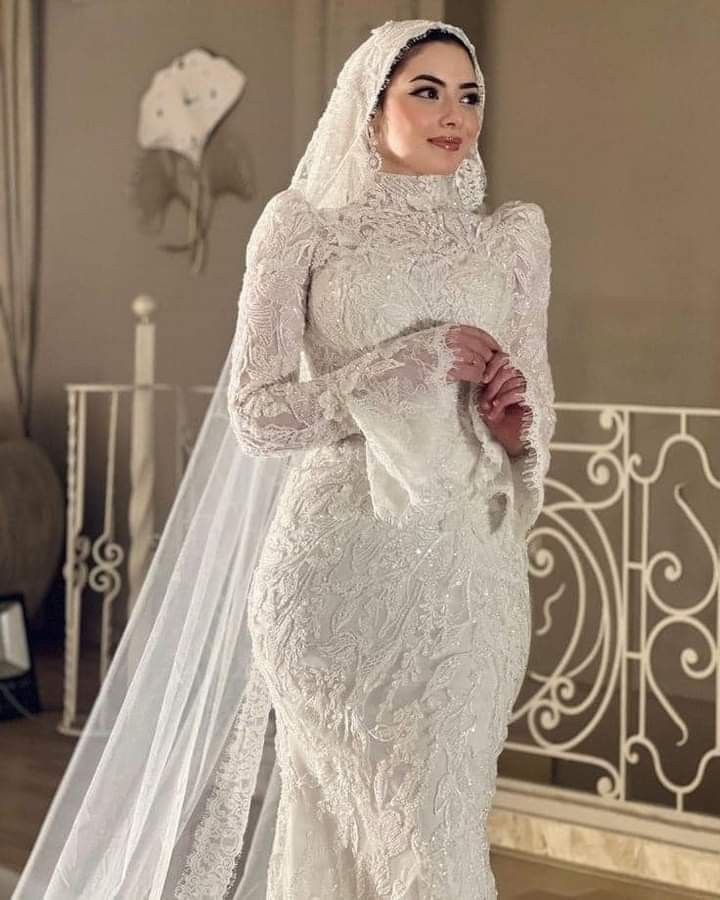 a woman in a white wedding dress and veil posing for the camera with her hands on her hips