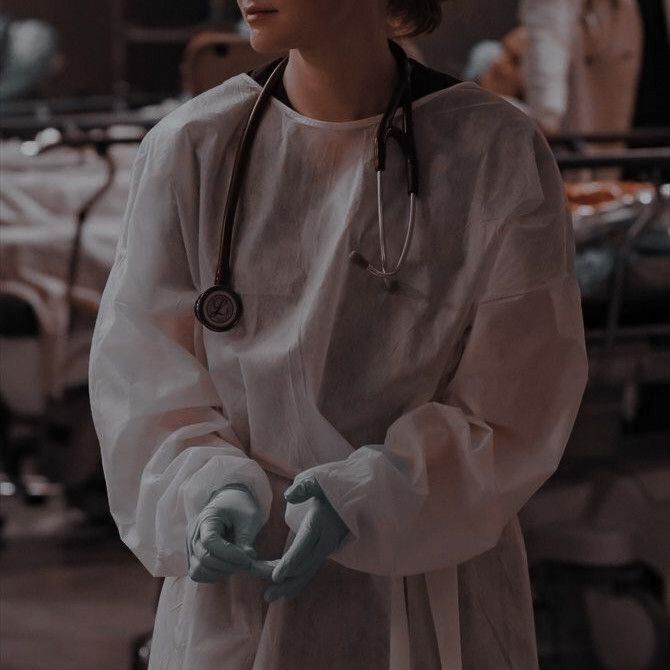 a woman in white scrubs stands with her hands on her hip and wears a stethoscope around her neck