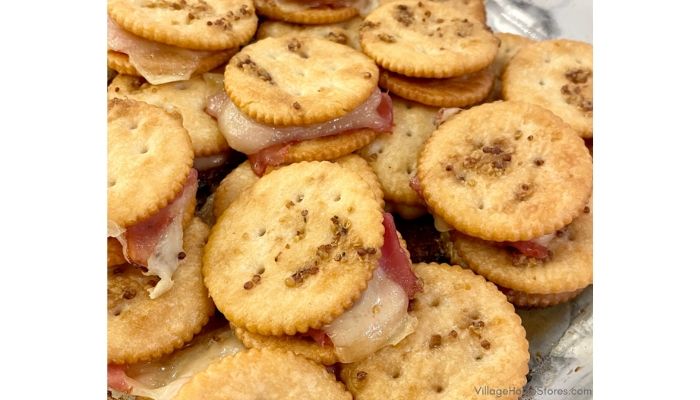 some crackers are sitting on top of each other in tin foil with toppings