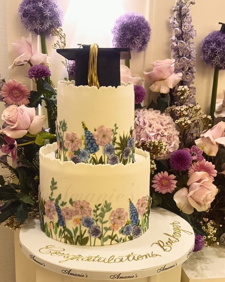 a three tiered cake decorated with flowers and a graduation cap on top that reads congratulations