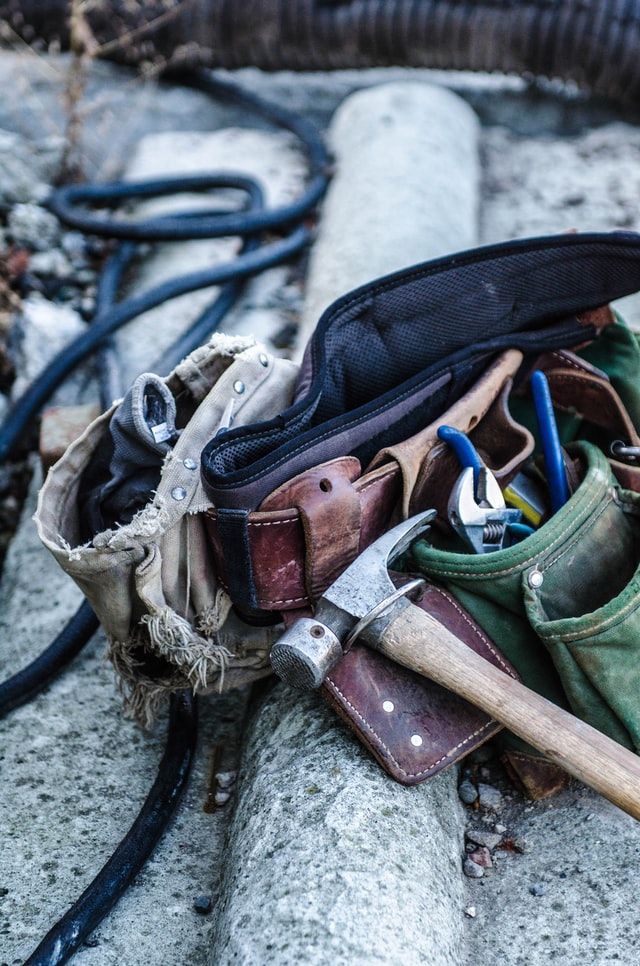 an assortment of tools are sitting in a bag on the ground next to a hose