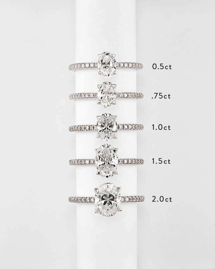 four different sizes of engagement rings on top of a white napkin with measurements for each ring