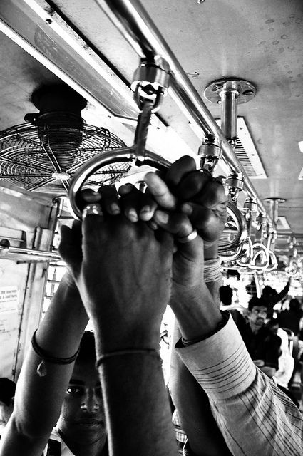 black and white photograph of people holding up their hands to the ceiling on a bus