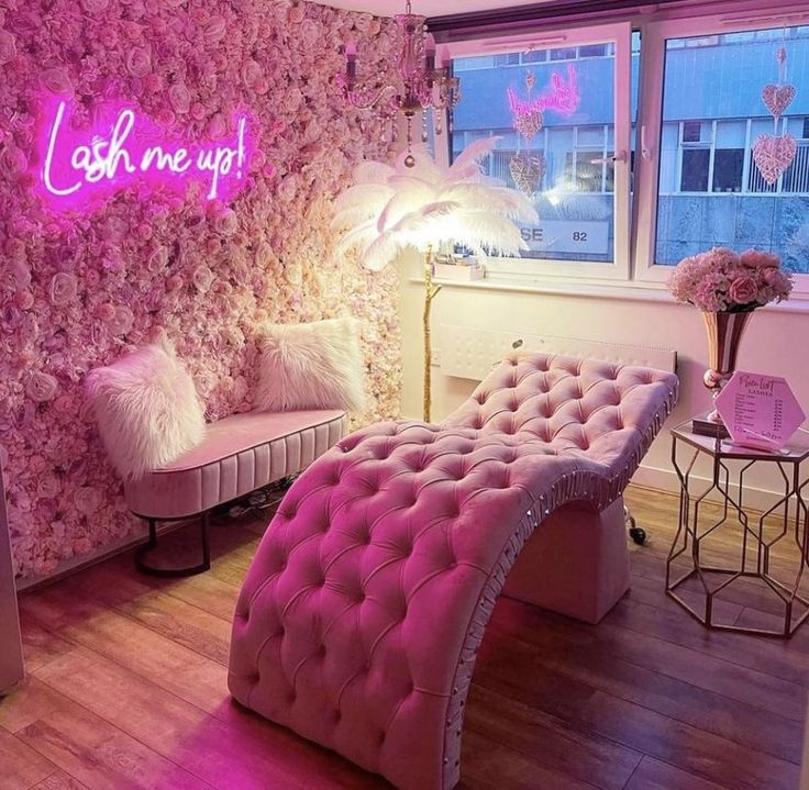 a room with pink furniture and flowers on the wall, along with a neon sign that says cash me up